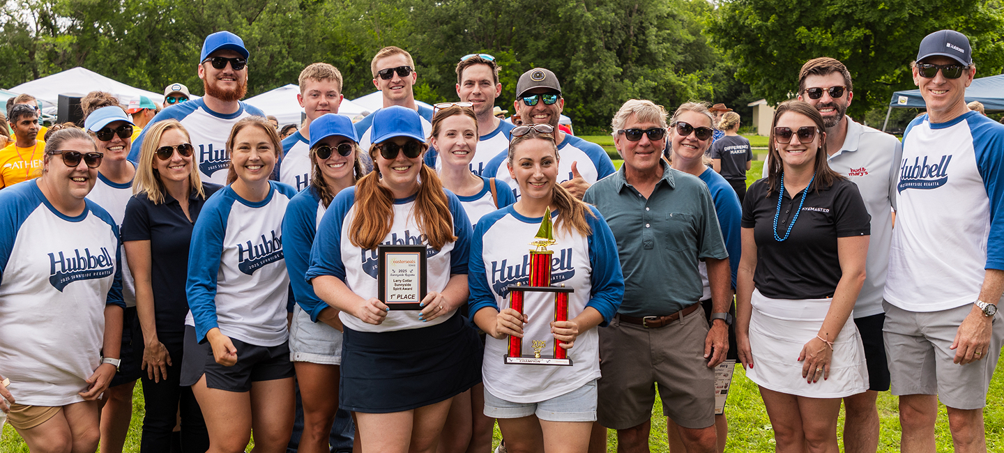 Group photo of a sports or event team outdoors, with individuals holding a trophy and plaque.