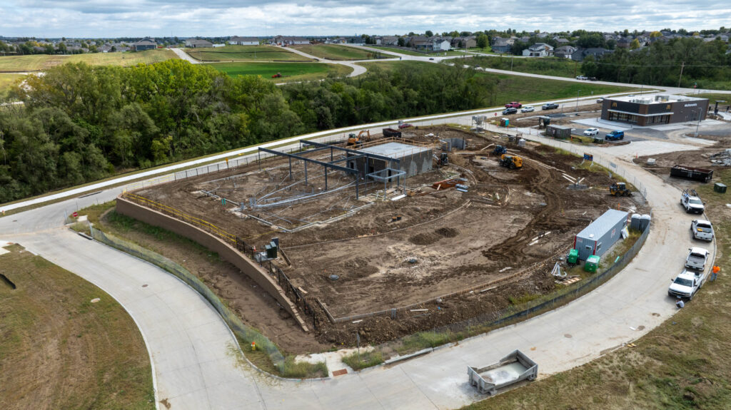 Construction site with heavy equipment and the steel frame of a building taking shape.