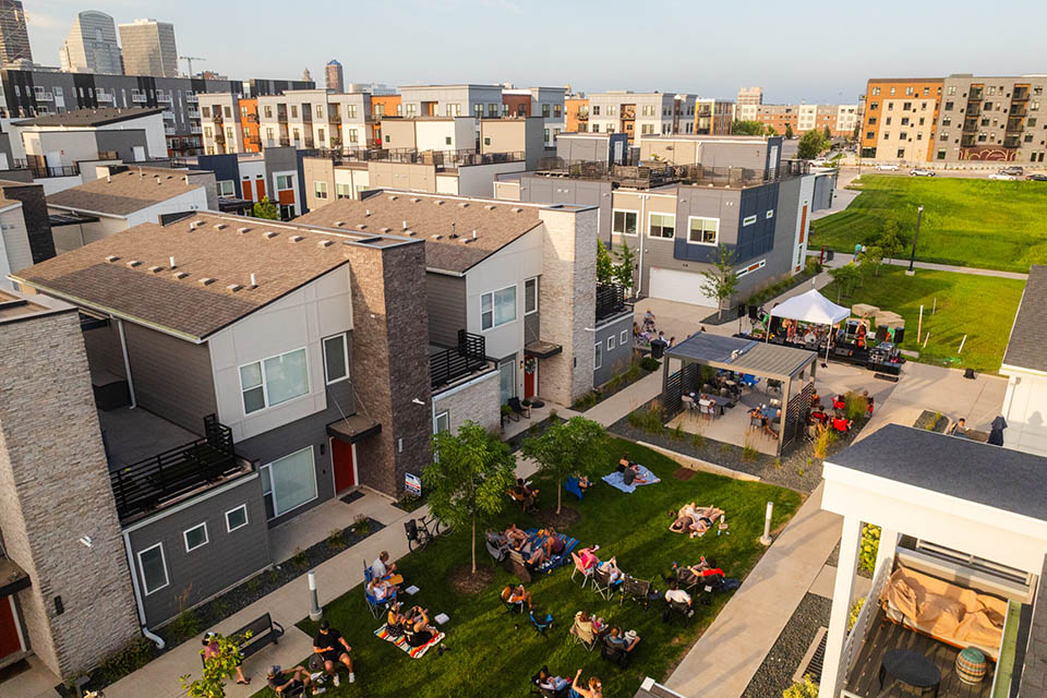 Aerial view of a residential community courtyard with people sitting on the lawn and a covered patio area.