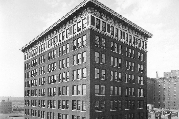 Historic Hubbell brick mid‑rise building with many windows, photographed in black and white.