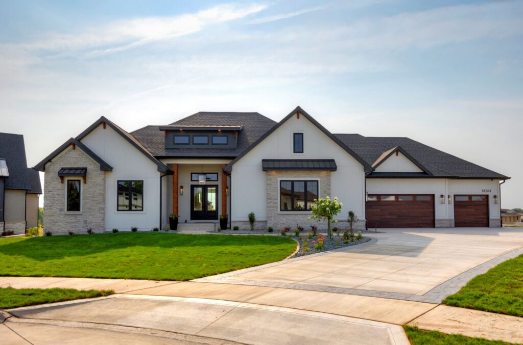 large custom home with three car garage, metal roofing, and green landscaping