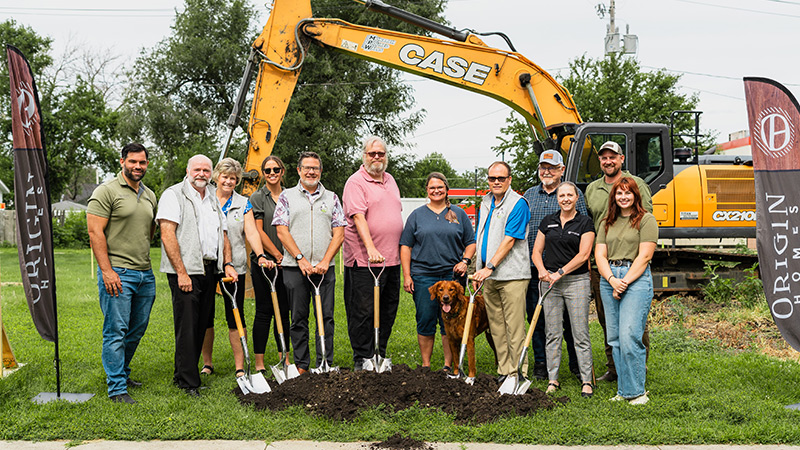 Team of employees standing with shovels by the newly broken ground