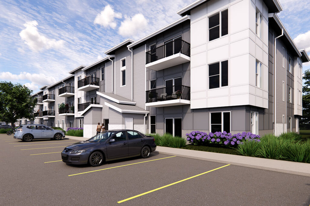 Rendering of a three‑story apartment building (The Rye at Harrison - Phase 1) with gray and white siding, black railings on balconies, and parking spaces along the front.