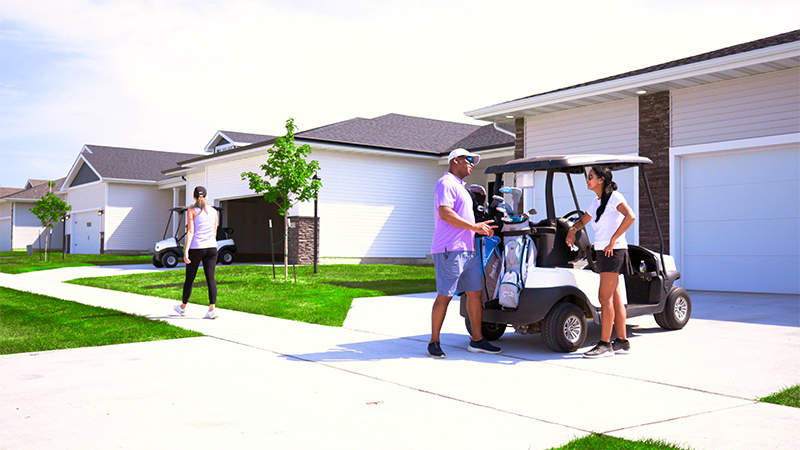 Two people speaking together outside a home with a golf cart