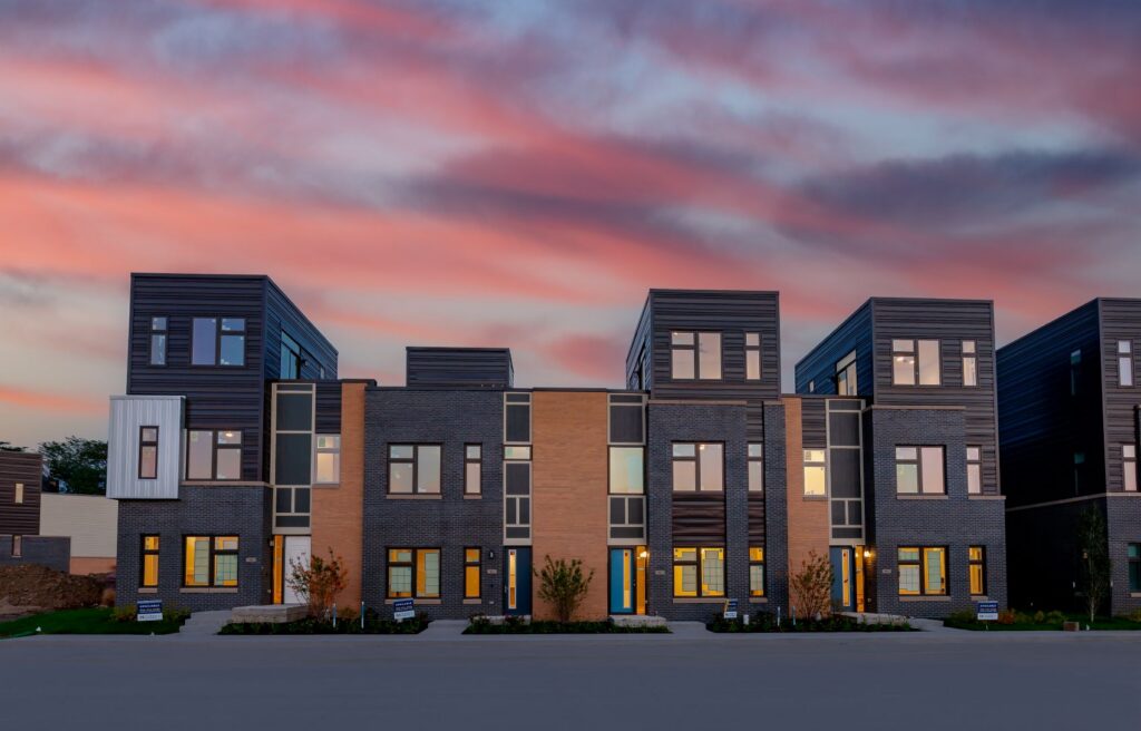 a row of townhomes with a pink sunset