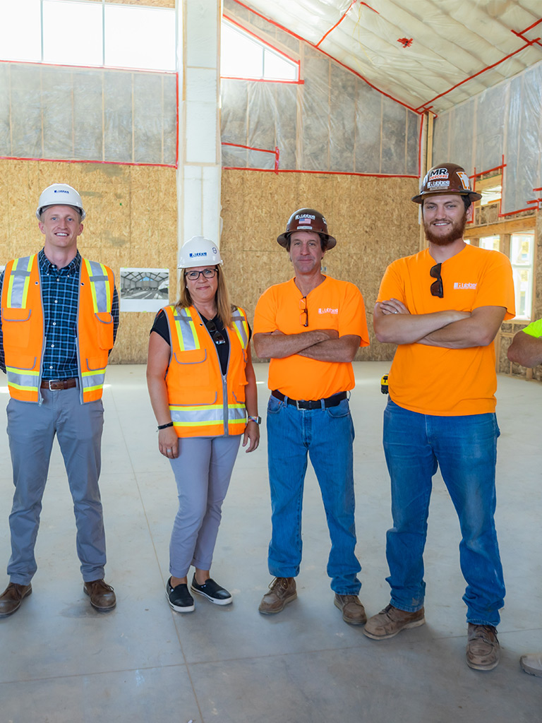 Four employees wearing fluorescent vest and hard hats in a construction area