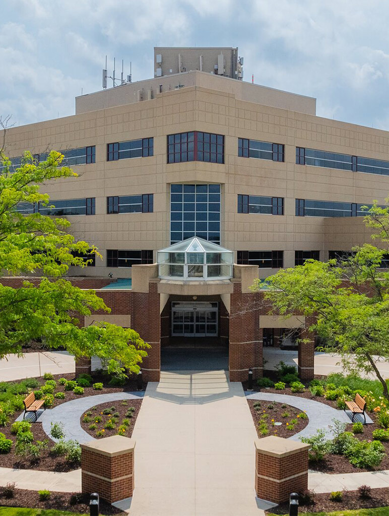 An aerial view of a brown stone commercial building featuring many windows and a large sidewalk leading up to it