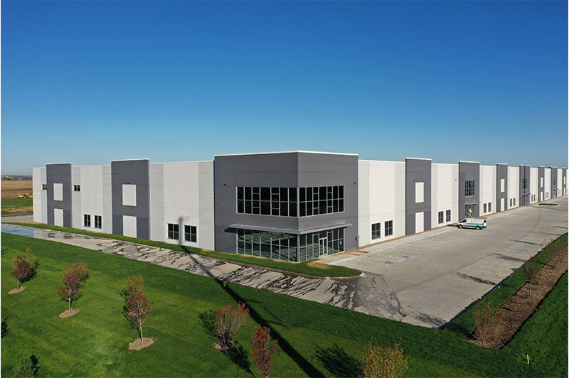 Close exterior view of the Hubbell Infinity Industrial Center Building featuring its glass entry corner and long row of warehouse bays.