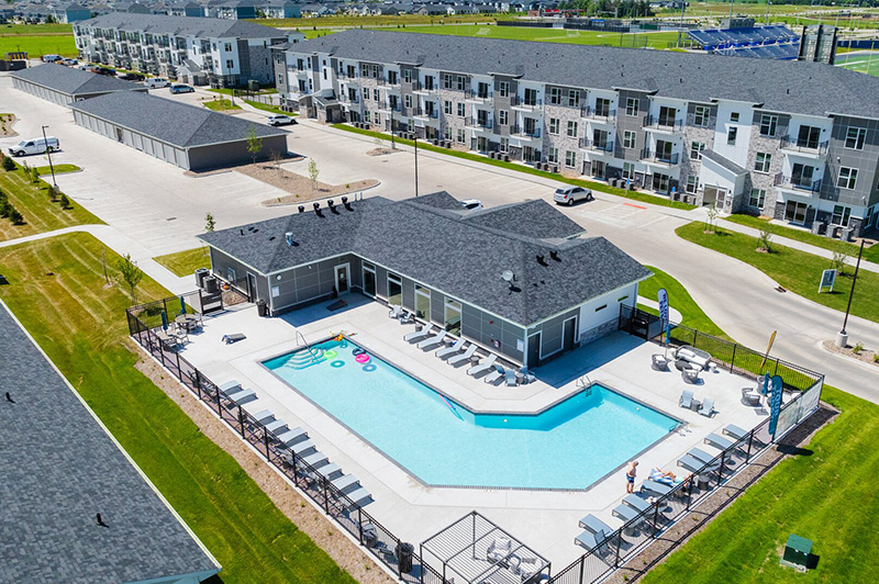 Aerial view of a large apartment complex and a clubhouse with a pool