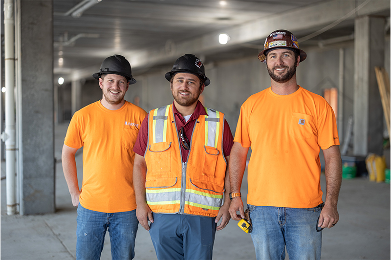 Three construction coworkers smiling together at a contruction site