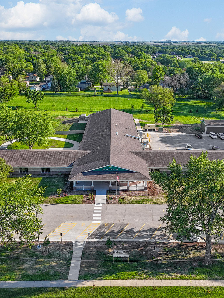 Aerial front entrance view of the Hubbell‑built On With Life Long Term Skilled Care Facility showing its central covered entry and surrounding landscaping.