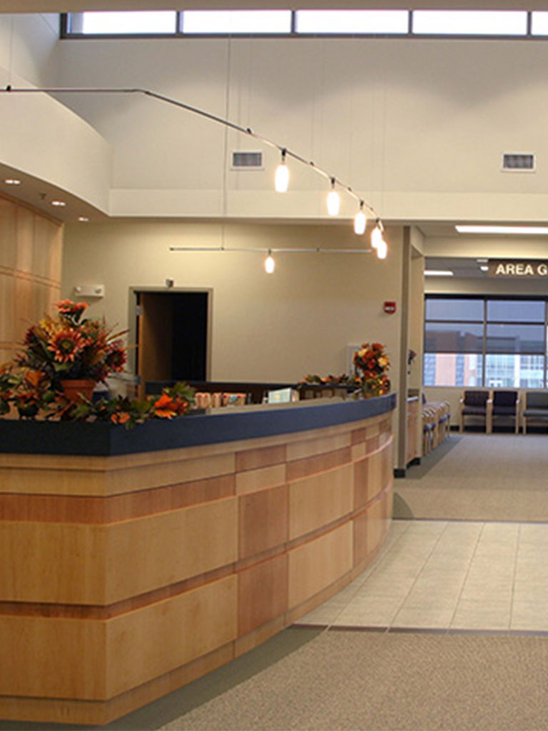 Lobby view of the Hubbell‑built Wolfe Eye Clinic highlighting the curved reception desk with floral décor and adjacent waiting area labeled ‘Area G.’