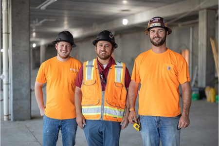 Three construction coworkers smiling together at a contruction site